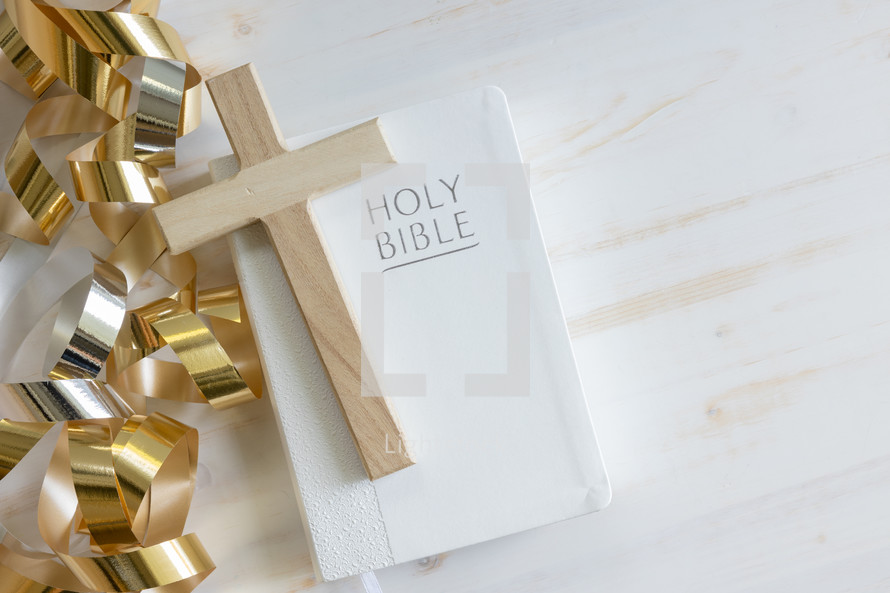 gold streamers and Bible on a white background