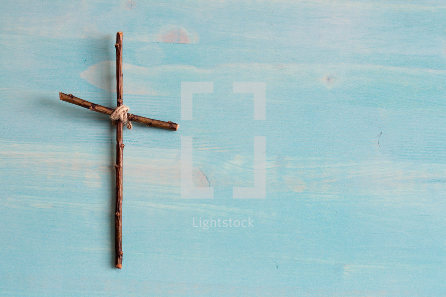 simple cross of sticks on a blue wood background 