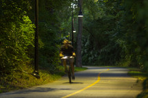 Man riding a bike on a paved trail at night.
