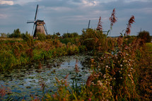 A windmill alongside a river.