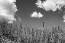 wooden cross in a field of tall grass 