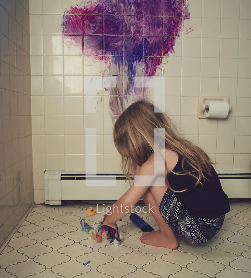 a child painting a bathroom tile wall 