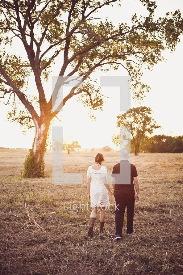 couple walking hand in hand through a field