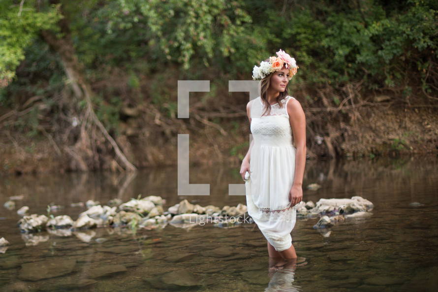 woman in a white dress and flowers in her hair walking in water 