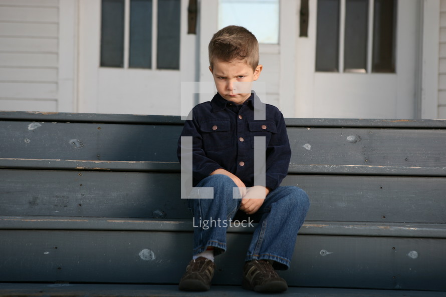 pouting boy sitting on stair steps