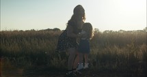 Happy mother playing with daughter in summer sunset.