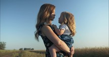 Happy mother and daughter laughing outside on farm in sunset