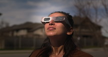 Woman finishes watching solar eclipse in front yard - takes off glasses