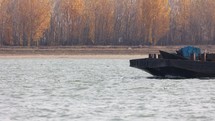 Dry Bulk Cargo Barge Being Pushed By A Towboat Across The Danube River With Autumn Foliage In Background. static
