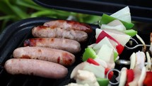 Turning Sausages Cooking on a Barbecue with Metal Tongs, Ireland
