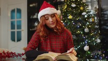 Girl studying on the book against Christmas tree