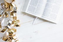 gold streamers and open bible on a white background