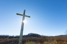 Sunlight on wooden Christian cross with nails in rural setting