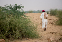 man walking through sand in India 