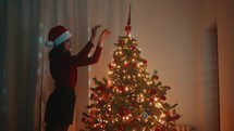 Girl decorate the Christmas tree alone in the house