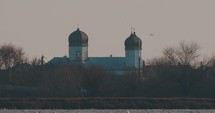 Church In Tulcea With Flock Of Seagulls Swimming In Danube River In Foreground At Sunset In Romania. - wide static