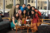 Group of young people posing for a picture, all of different ethic backgrounds, in a waiting room
