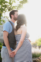 expecting couple holding hands outdoors 