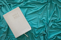 White bible on a teal blanket background