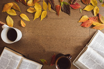 Open bibles, coffee cups and autumn leaf frame on a wood background with copy space