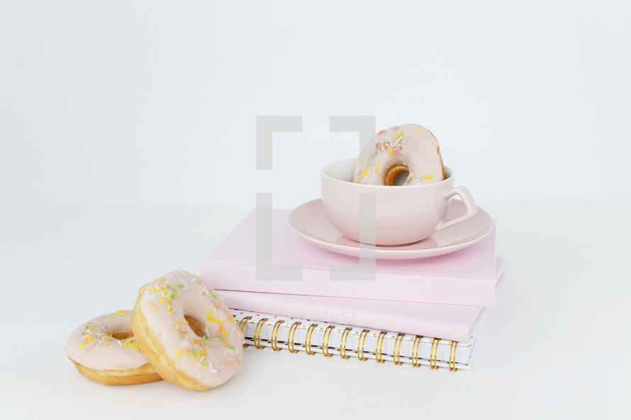 coffee and donuts on a stack of pink notebooks