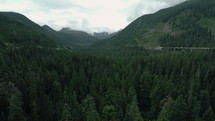 aerial view over a valley forest and mountain highway