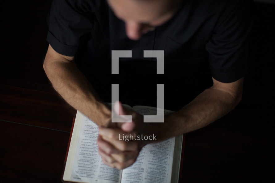 A minister prays over an open Bible.