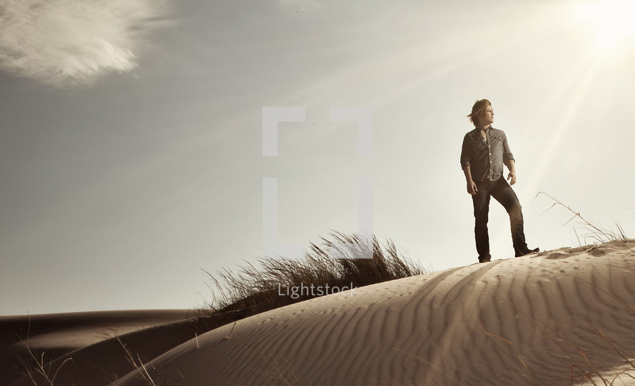 man standing on top of a sand dune