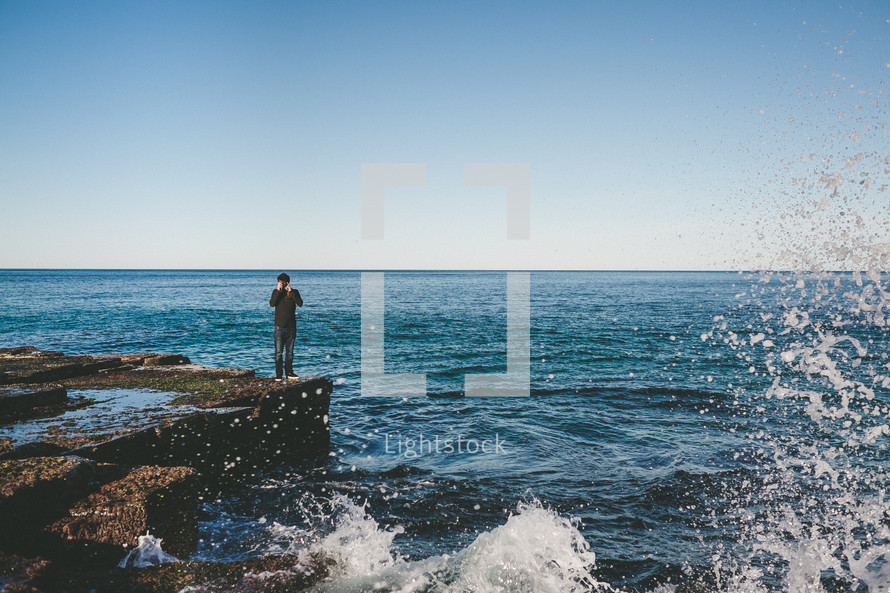 man standing on a rock by the ocean 