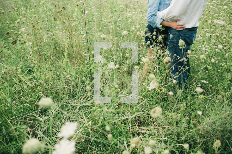 a couple embracing in a field of tall grasses 