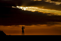 silhouette of a man with a telescope at sunset 