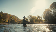 Young fly fisherman casting on a foggy river at sunrise