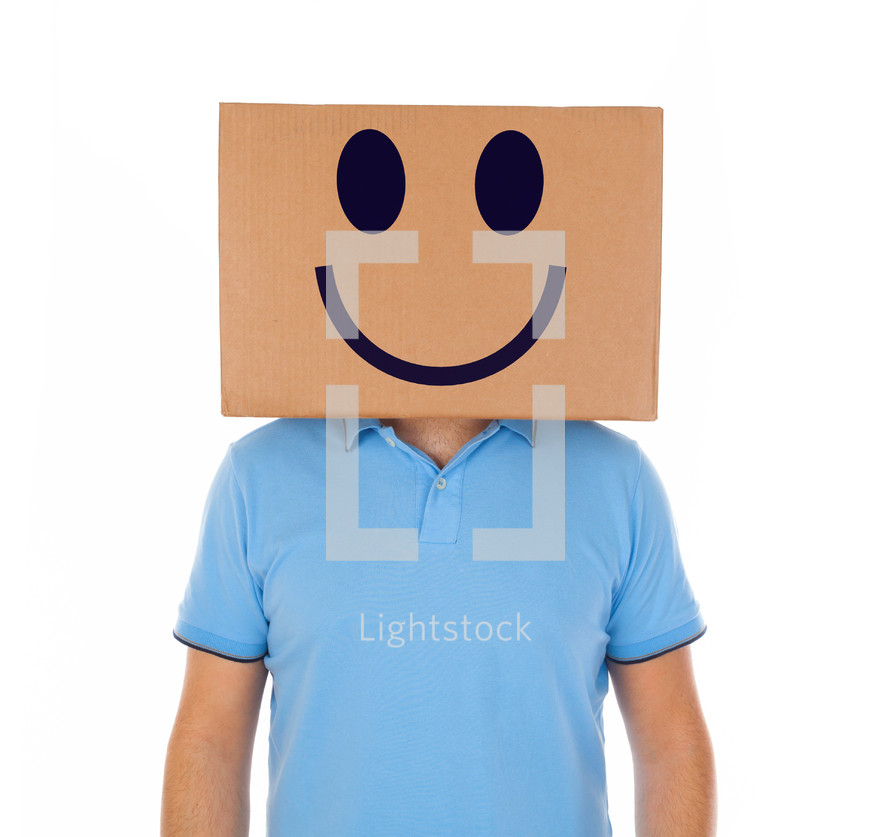 Young man standing with a cardboard box on his head with smiley face on white background.