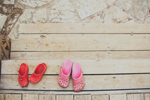 Shoes on the steps of a wooden deck outside.