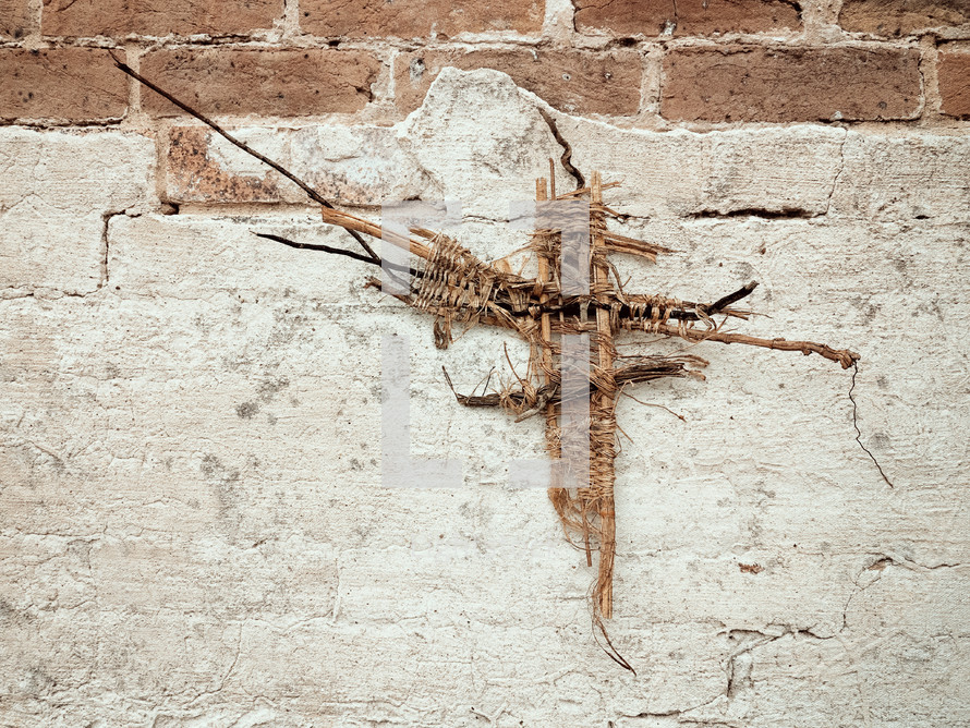 woven cross on a brick wall 