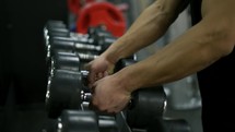 Man hands take dumbbells from gym stand. The concept of sports and active lifestyle.
