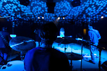 Musicians performing on a stage view behind drummer worship service team 