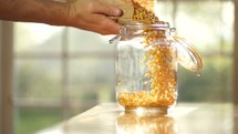 pouring corn kernels in a jar 