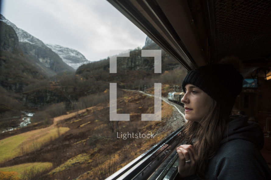 a woman traveling on a train looking out a window 