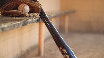 baseball glove and bat in a dugout 