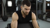 Handsome bodybuilder doing weight lifting in gym, close up.