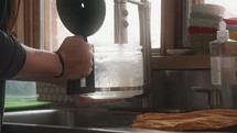 a woman filling up a coffee pot with water 