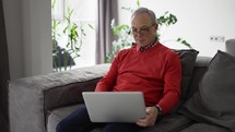 Smiling senior man wave to camera having video call on laptop.