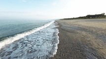Calm ocean near an empty sandy beach coast
