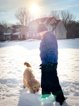 boy and dog playing in snow 
