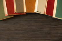 Border of vintage books on a dark wood table from above