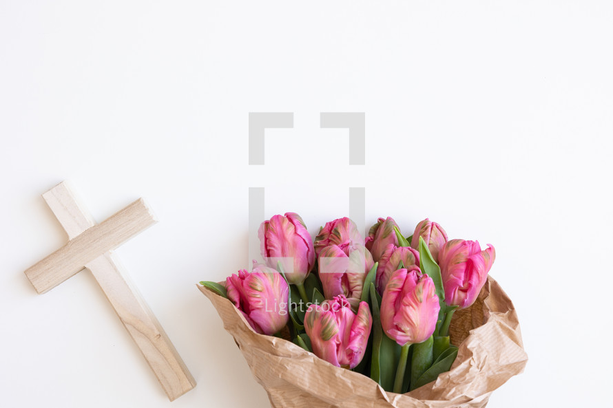 Wood cross with bouquet of pink tulips on a white background