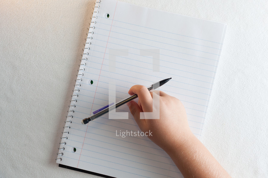 a child writing in a spiral notebook 