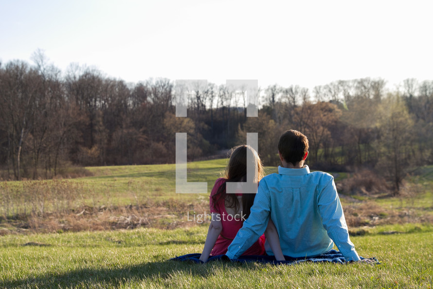couple sitting together on a blanket in grass 