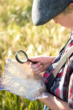 a boy looking at an old map with a magnifying glass 